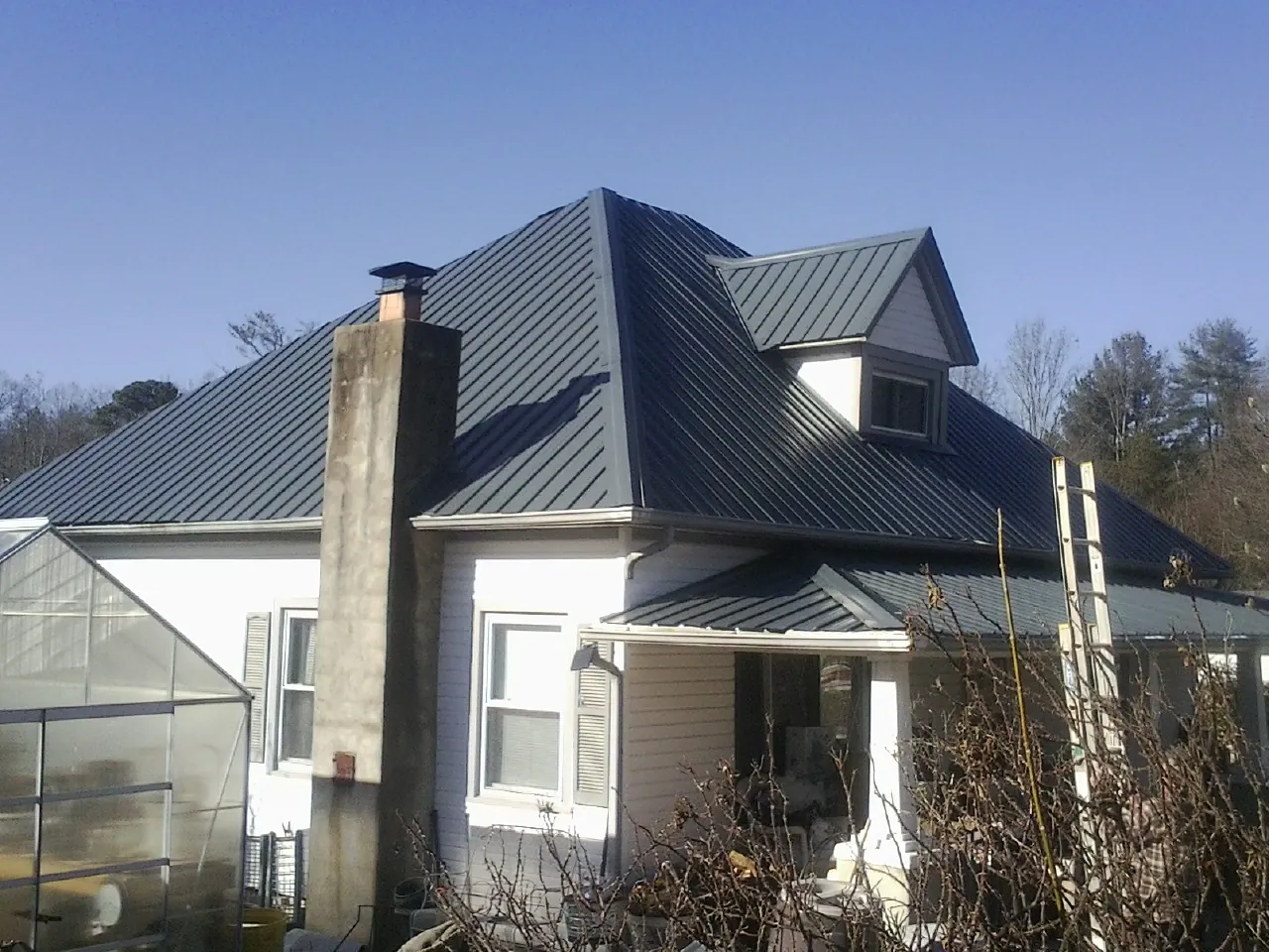 Dark blue standing seam metal roof on a white farmhouse with dormer — Slate & Tile Roof Repair by Roofing Brothers in Ventnor City