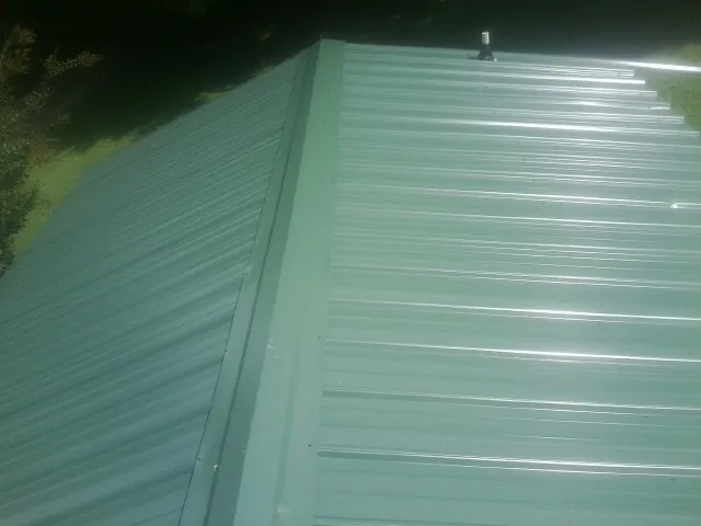 New green metal panels meeting at the ridge of a roof — Flat Roof Repair work by our crew in Ventnor City