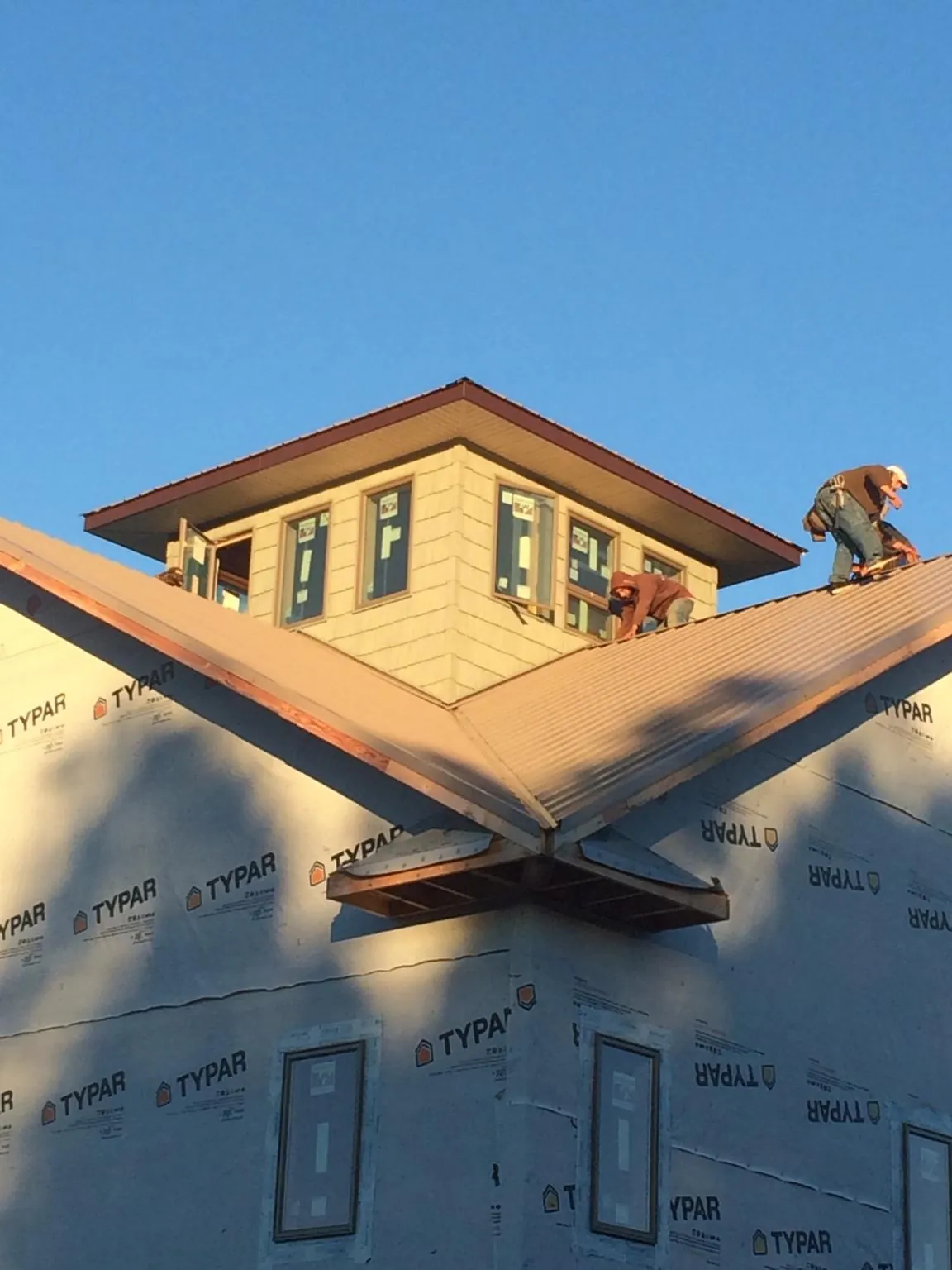 Roofers working around a rooftop cupola on a new metal roof at sunset — Roof Waterproofing in Ventnor City by Roofing Brothers